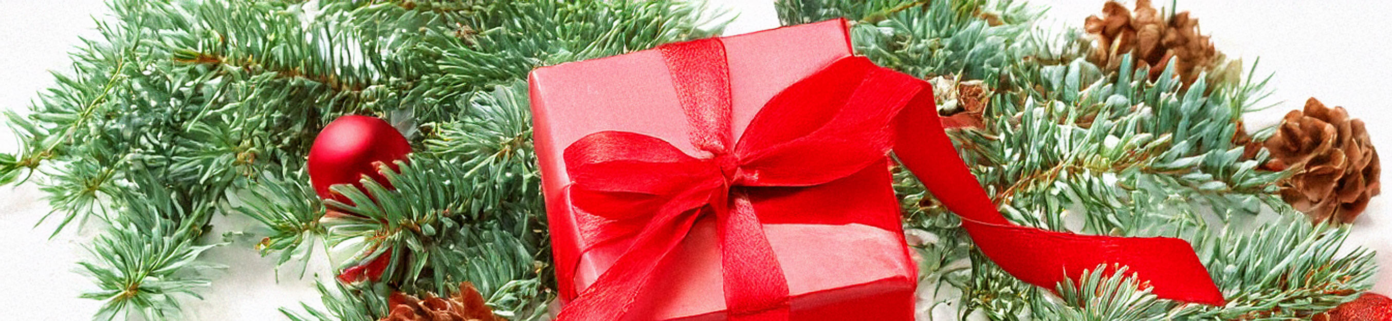 Weihnachtsgeschenk in roter Verpackung mit Rosenkranz und Tannenzweig