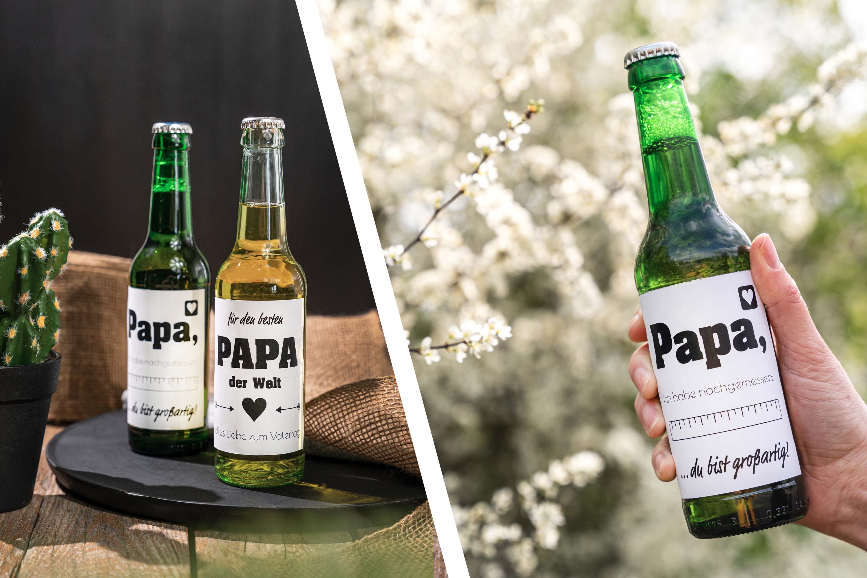 Drei Bierflaschen mit "Papa" Etiketten auf Tisch. Bierflasche mit Vatertags-Etikett vor Blüten.