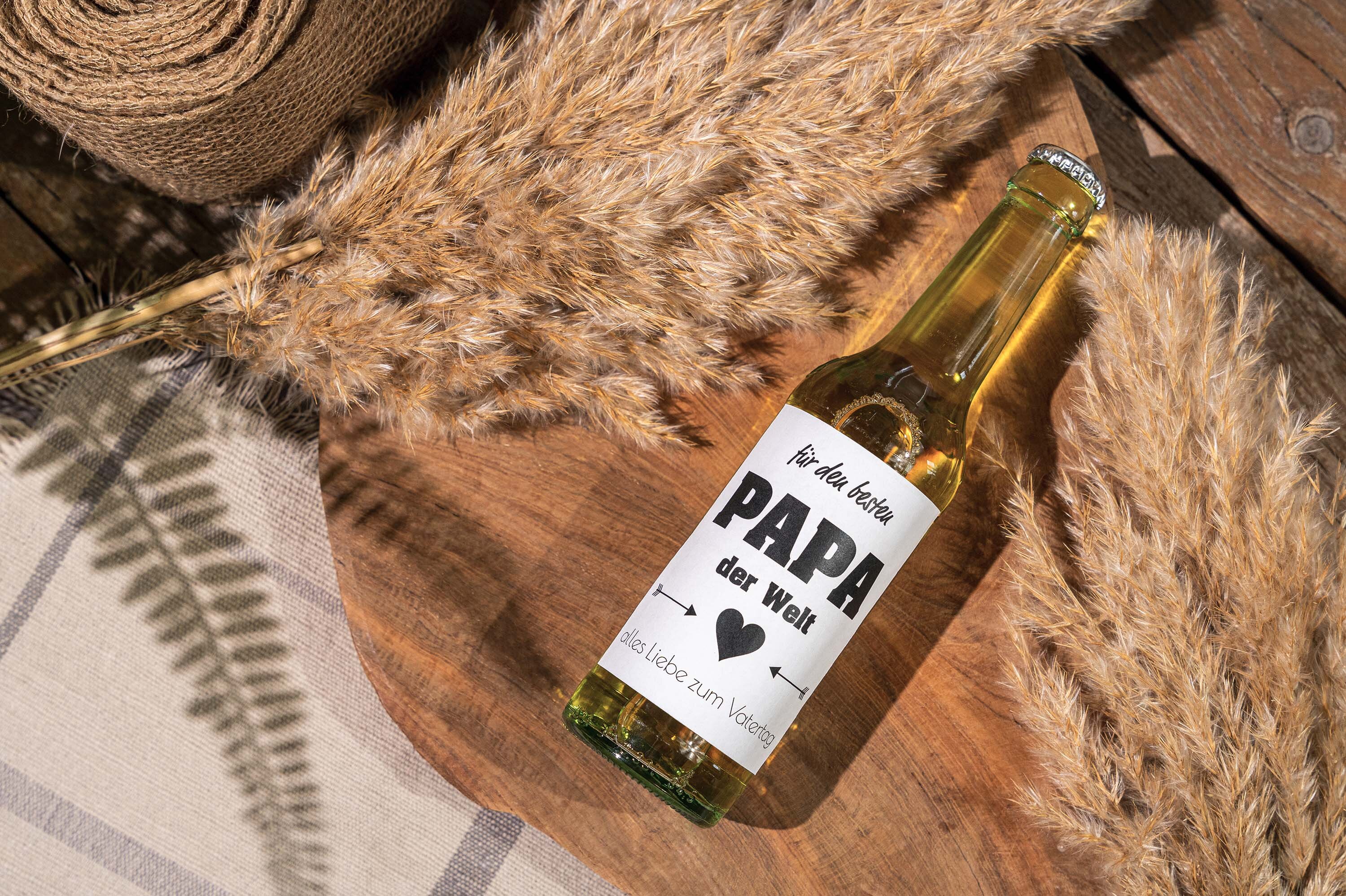Bierflasche mit "Papa der Welt" Etikett auf Holzbrett.