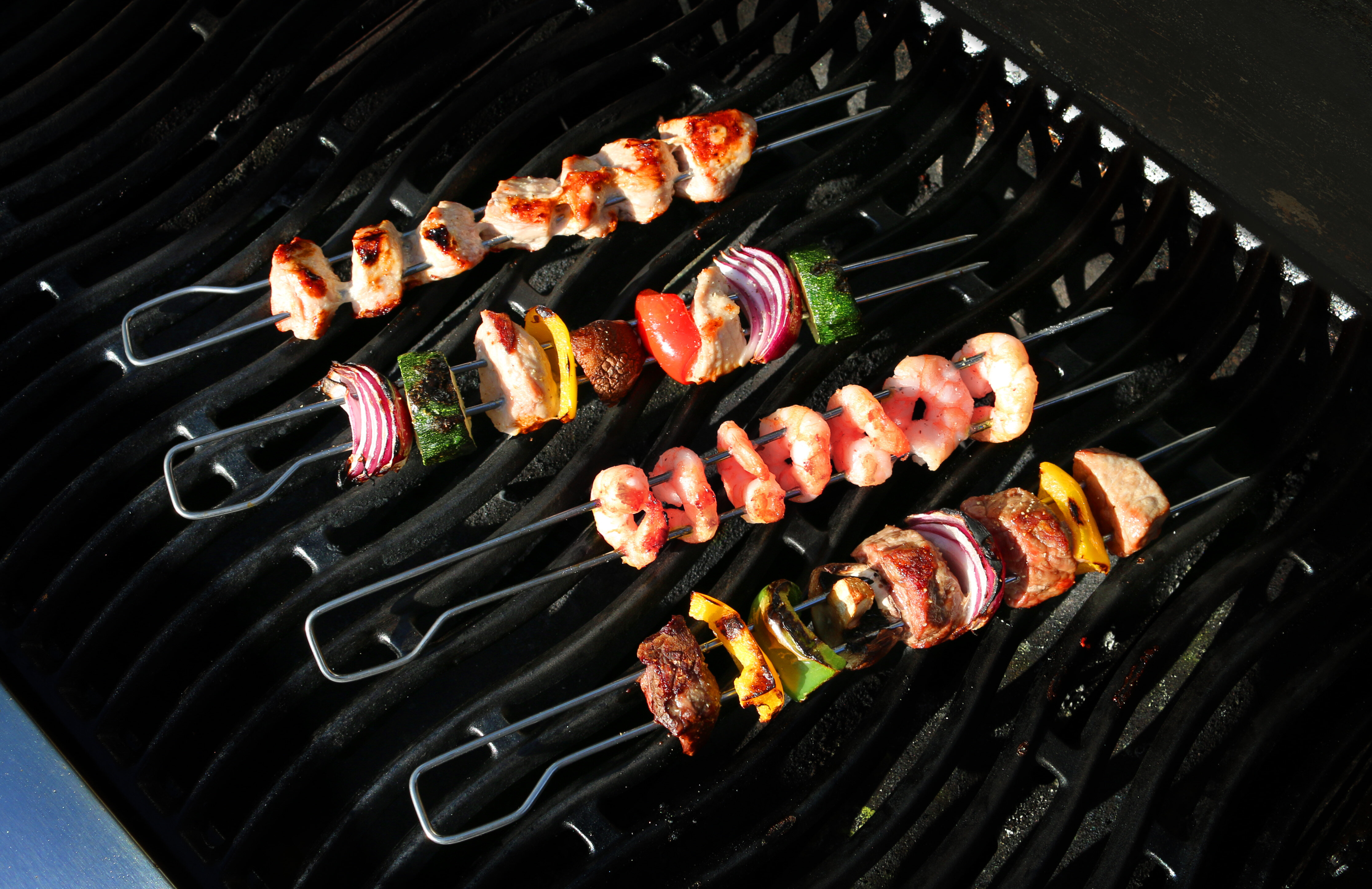 Ein Grill mit mehreren Spießen, die auf dem Rost zum Garen vorbereitet sind. 
