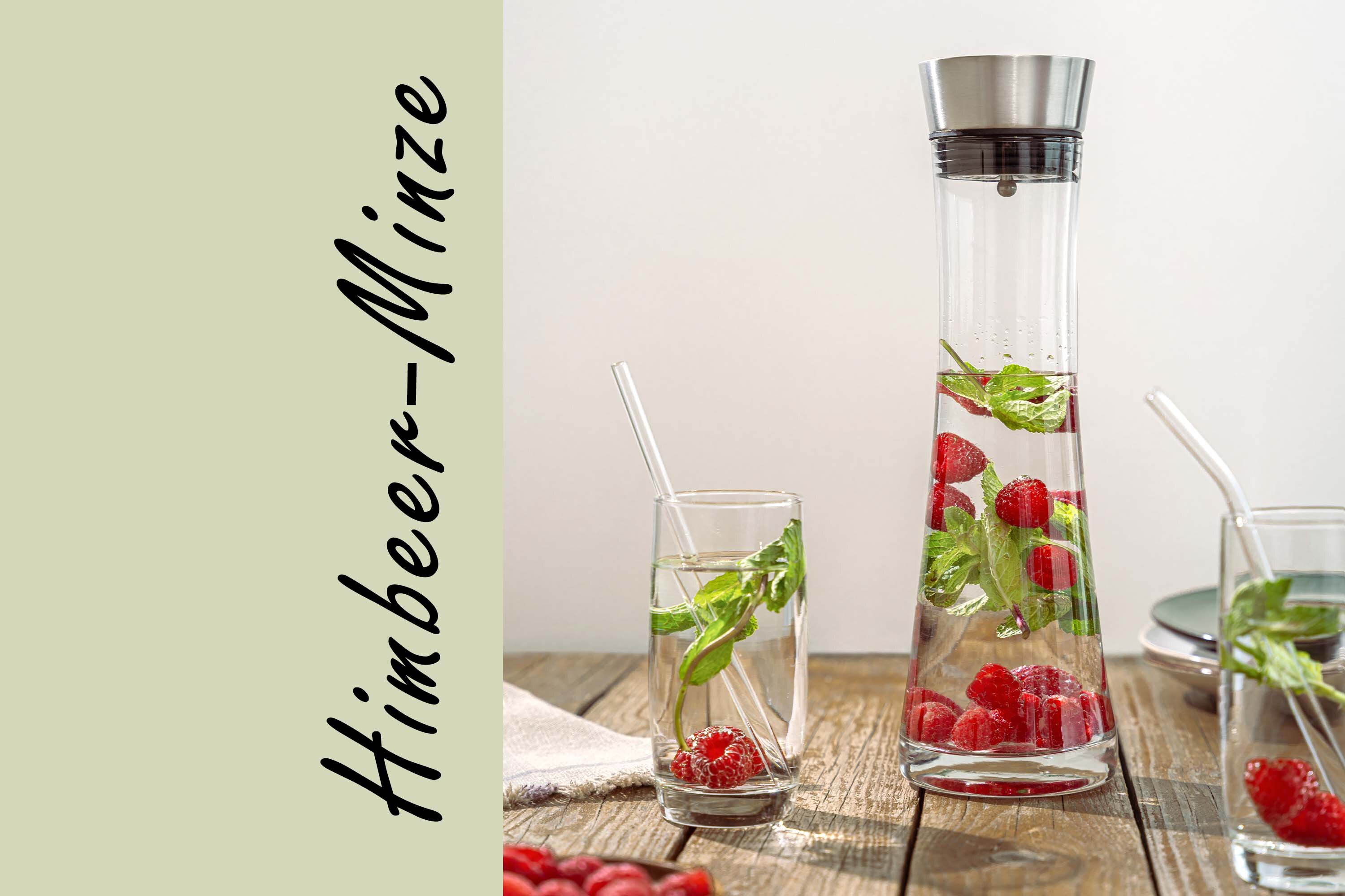 Eine Glaskaraffe mit Himbeeren und Minzblättern steht auf einem Holztisch. Zwei Gläser mit Strohhalmen sind daneben platziert. Der Text 'Himbeer-Minze' ist links in geschwungener Schrift.