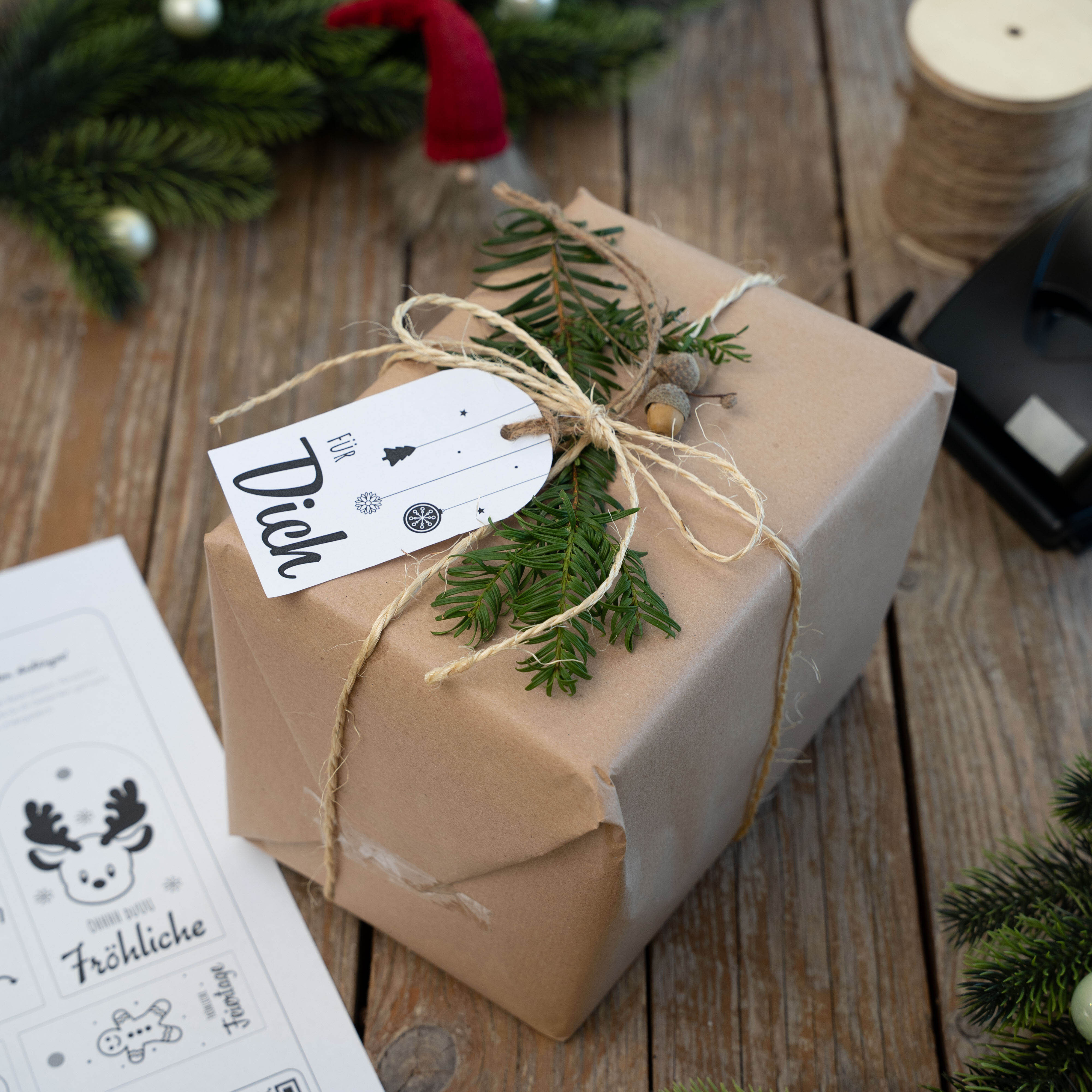 Braunes Geschenk mit Naturkordel, Tannenzweig und Anhänger mit der Aufschrift 'für Dich' auf Holztisch.