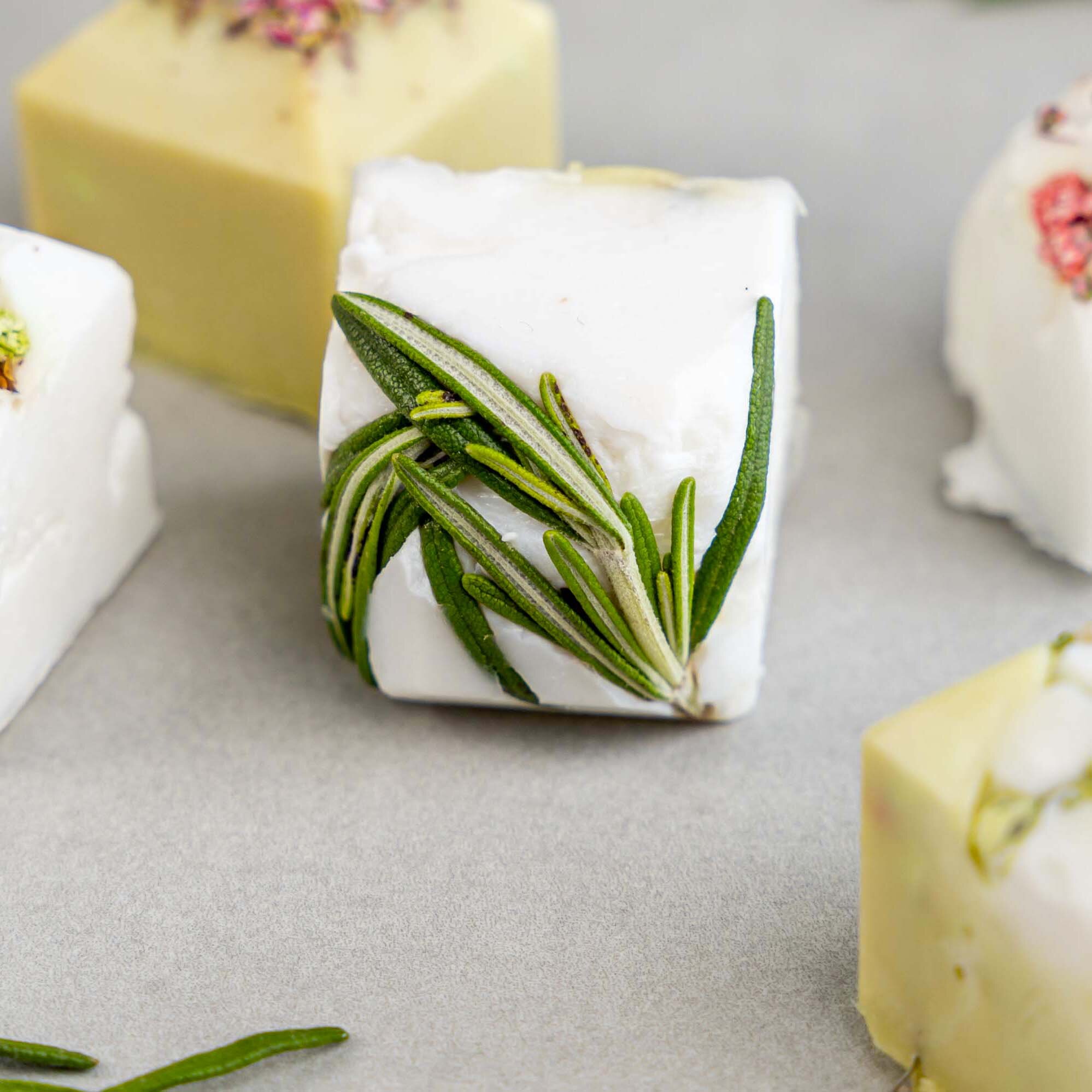 Handgemachte Seifenwürfel mit Rosmarin und Blüten.