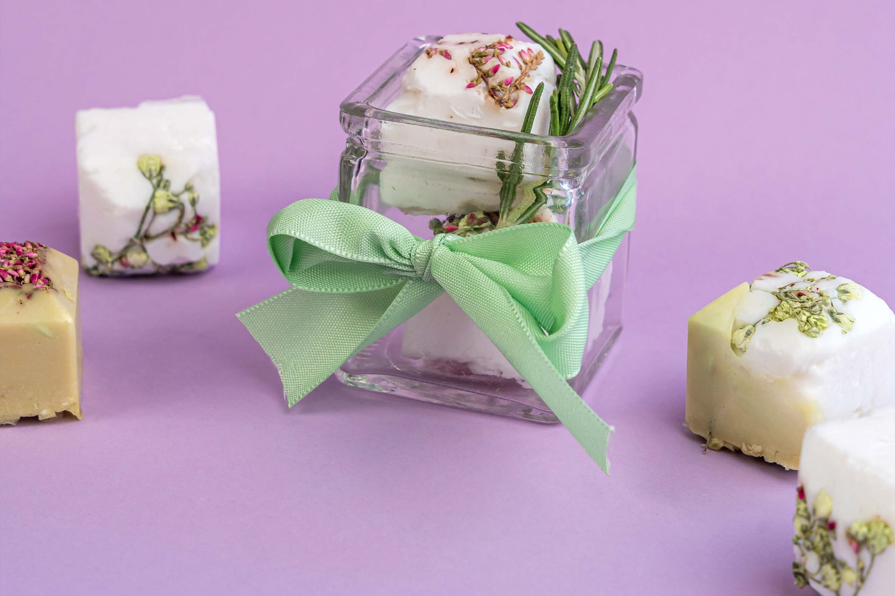 Nahaufnahme von handgemachten Seifenstücken mit Blumen und Spitze.