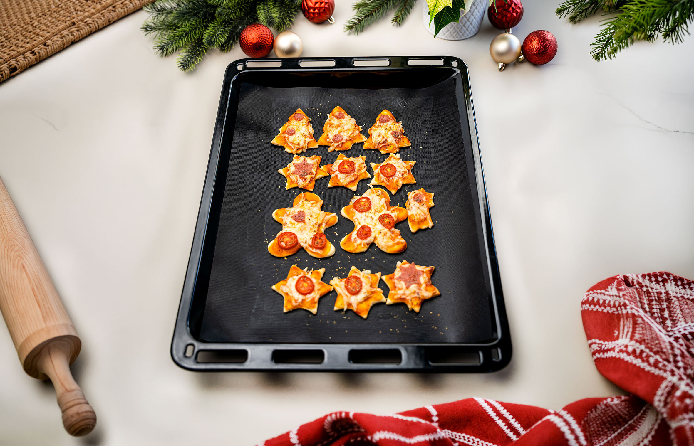Weihnachtsgebäck in Form von Bäumen und Sternen auf einem Backblech.