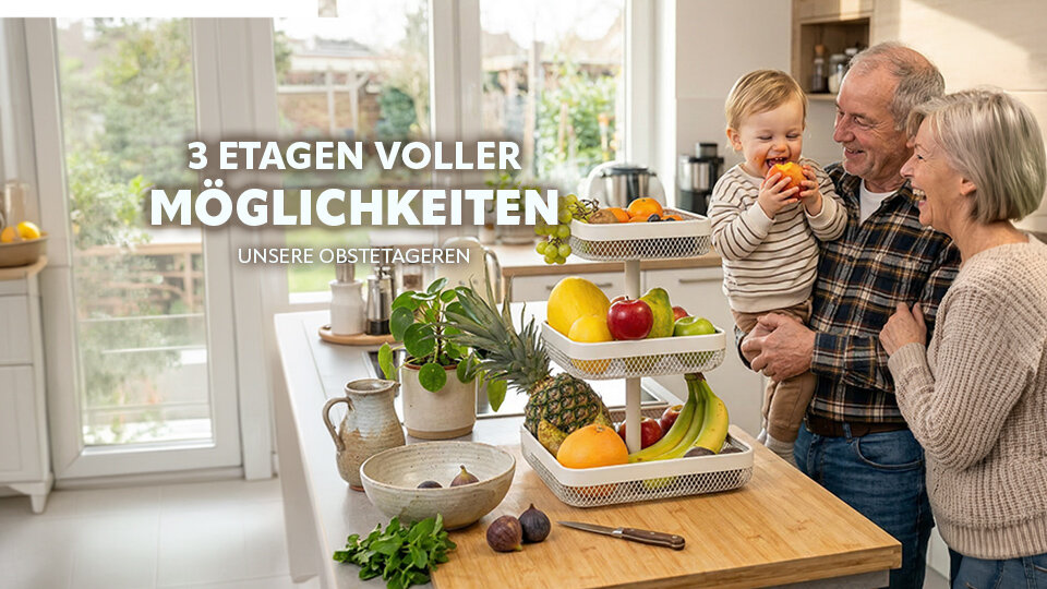 Dreistöckige Obstschale mit verschiedenen Früchten auf einer Küchenarbeitsplatte, im Hintergrund ein Mann hält ein Kleinkind