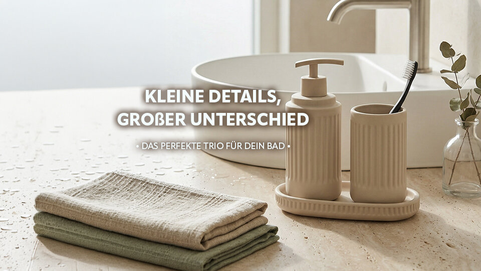 Badutensilien mit Seifenspender, Zahnputzbecher und Handtüchern auf einer hellen Oberfläche neben einem Wasserhahn